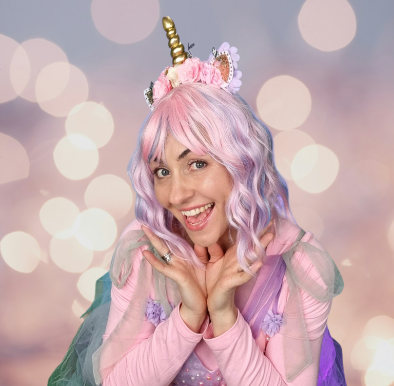 Unicorn kids' party Person with pink hair and unicorn headband, smiling against a blurred pastel background.