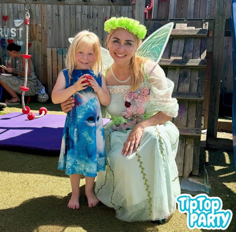 Kids joining in exciting group games at a children’s party. A fairy character poses with a smiling young girl in a blue dress, outdoors.